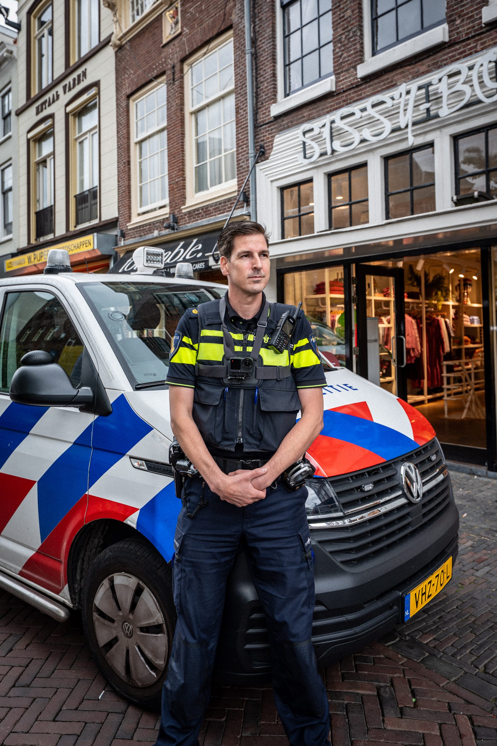 Omgevingsportret van een politieagent voor een politievoertuig